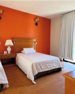a bedroom with an orange wall and a bed at Hotel y centro de convenciones MANSION INN in San Mateo Texcalyacac