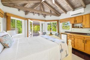 a bedroom with a bed and a kitchen with windows at Marjorie's Kauai Inn in Lawai