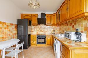 a kitchen with wooden cabinets and a black refrigerator at appartement proche paris et Roissy in Persan +21 photos