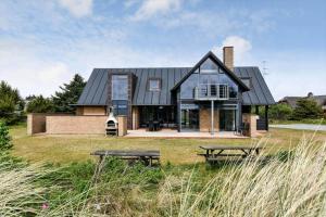 a house with a black roof and two picnic tables at BV284-Blavand-Blavand-Strand-4 in Blåvand