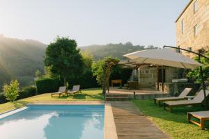 a pool with chairs and an umbrella next to a building at MONTD'OR Azenha - by RowdHouses in Paços de Gaiolo
