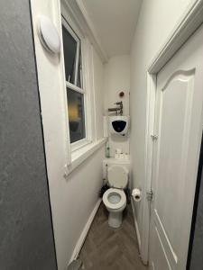 Un pequeño baño con inodoro y ventana. en Premier Apartmetns Manchester, en Mánchester