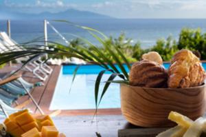 a bowl of bread and cheese on a table near a pool at Chez Marie & Philippe - La Villa By Ferdi'Nan in Grand-Bourg