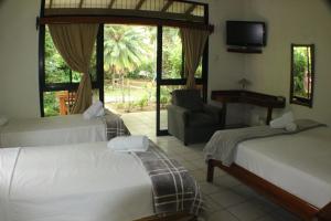 a bedroom with two beds and a chair and a television at Hotel Colinas del Sol in Atenas +44 photos
