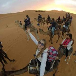 un grupo de personas montando camellos en el desierto en RIAD El YacouT, en Marrakech