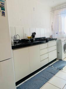 a white kitchen with a sink and a dishwasher at Calmo e aconchegante apartamento térreo com quintal in Valparaíso de Goiás