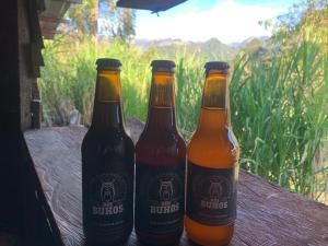 three bottles of beer sitting on a wooden table at Camping Dos Buhos in Líbano