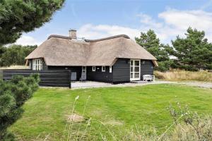 a small black house with a thatched roof at BV151-Blavand-Hedetoftvej-116 in Blåvand