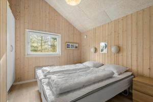 a bedroom with a bed in a room with wooden walls at BV313-Blavand-Hvidbjerg-Strandvej-40 in Blåvand