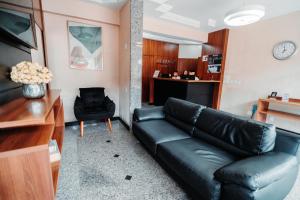 a living room with a black leather couch and a chair at Hotel Albinos in Itaperuna