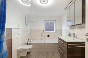 a bathroom with a tub and a toilet and a sink at Klaus Lafrenz Petetsdorf Nr 1 in Fehmarn +19 photos
