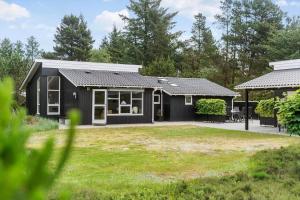 a black house with a yard in front of it at BV325-Blavand-Tvaervaenget-8 in Blåvand
