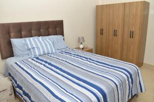 ein Bett mit einer blau-weiß gestreiften Decke und einem Holzschrank in der Unterkunft Casa de La Reina in Chiclayo