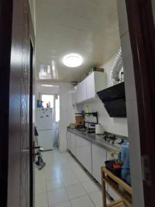 eine Küche mit weißen Schränken und einem Kühlschrank in der Unterkunft Shoucheng international 2104 in Peking