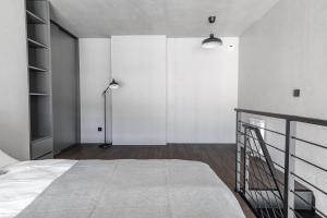 a white bedroom with a bed and a lamp at Sea Loft 49 in Gdynia