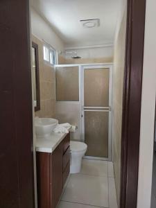 Un baño con dos lavabos, un inodoro y una ducha. en Hostal Boutique Isabel, en Managua