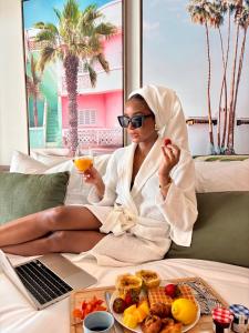a woman sitting on a bed with a plate of food and a laptop at Suite 2 Mogador Residence, 2BR, brand-new, rare and luxury, sea view in Grand Case +36 photos