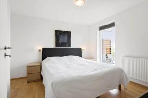 een witte slaapkamer met een bed en een raam bij 0387-Romo-Nordre-Havnevej-18 in Havneby