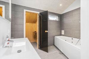 een badkamer met een wit bad en een wastafel bij 0200-Romo-Elmegardsvej-10 in Tagholm +20 foto's