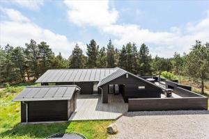 een huis met een zwart dak en een terras bij 0200-Romo-Elmegardsvej-10 in Tagholm