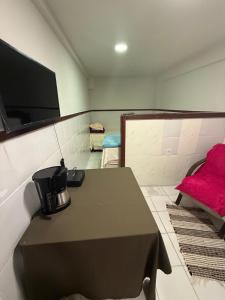 a room with a table and a tv on the wall at Hospedagem no centro da cidade! in Macaé