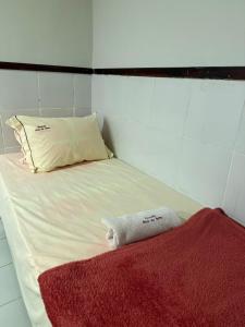 a small bed with a red blanket and a pillow at Hospedagem no centro da cidade! in Macaé