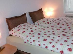 a bed with a white and red comforter on it at Holiday home in Rügeband with swimming pool 