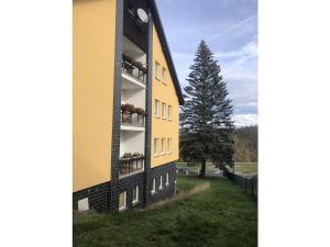 a yellow and black building with a tree in the background at Schwarzatal meadow view in Schwarzburg +2 photos
