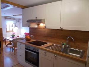 ヴァルタースドルフにあるOne-bedroom apartmentの白いキャビネットとシンクとテーブルのあるキッチン