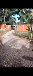 an empty road with an orange fence and trees at Raízes kit net in Itacaré