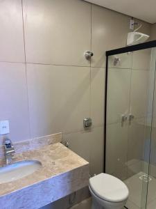 a bathroom with a sink and a toilet and a shower at suítes Pousada Catuira 1 in Araxá