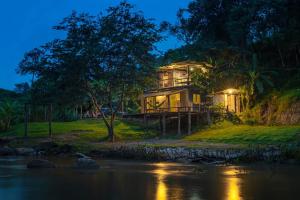 a house on the side of a river at night at Le Cher campsite & homestay in Ban Yang Huai Tong
