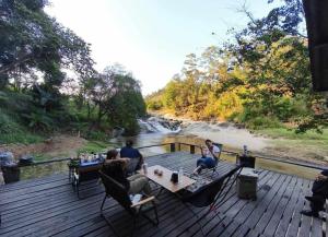 a group of people sitting on a deck next to a river at Le Cher campsite & homestay in Ban Yang Huai Tong