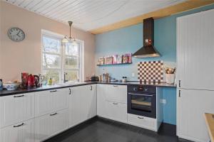 a kitchen with white cabinets and a clock on the wall at 15505-Farevejle-Tjornebakken-9 in Fårevejle