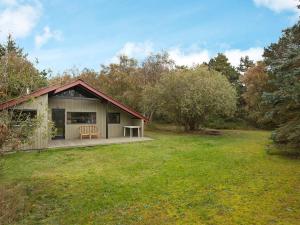 a small house with a deck in a field at Holiday Home Escape in Scenic Rodby in Rødby