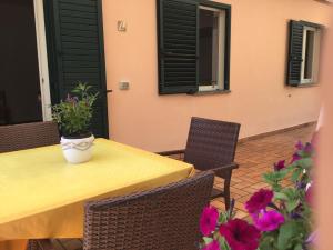 a yellow table with chairs and flowers on a patio at Villarosamaratea in Maratea