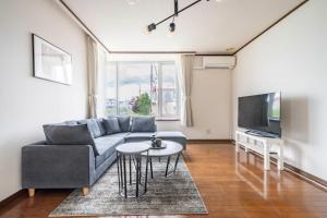 Una sala de estar con un sofá y un televisor. en Sekka, en Furano