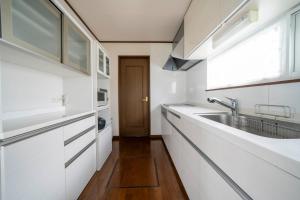 Una cocina con gabinetes blancos y un fregadero. en Sekka, en Furano