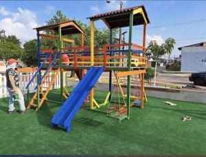 a man standing next to a playground with a slide at Casa Cop 30 em condomínio in Ananindeua