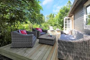 a patio with wicker chairs and a table on a deck at 16664-Farevejle-Klinteborgvej-7 in Fårevejle