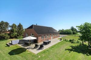 a brick building with a table and chairs and an umbrella at 0003-Romo-Vestervej-39 in Toftum