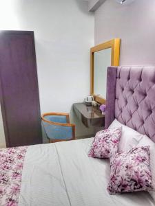 a bedroom with a bed with a purple headboard and a table at Villa Aanya in Katunayake