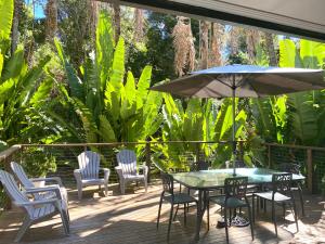 a patio with a table and chairs and an umbrella at Ferns Hideaway Resort in Byfield