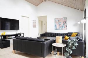 a living room with black leather furniture and a flat screen tv at 13303-Asnaes-Hove-Straede-42-D in Asnæs