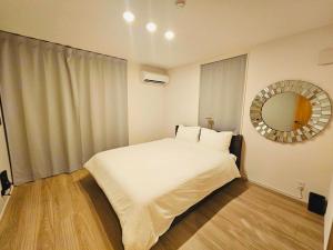 a bedroom with a white bed and a mirror at 希少新築 家族 グループ歓迎 国際通り近く 4泊以上10offキャンペーン中 in Naha