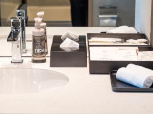 a bathroom counter with a sink and hygiene products on it at Hotel Crown Palais Kobe in Kobe