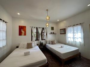 two beds in a room with white walls and windows at Rabbit Hole Villa in Boracay