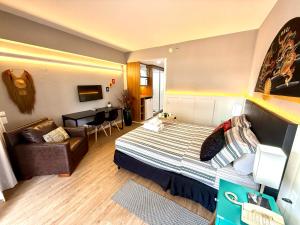 a hotel room with a bed and a couch at Lindo Studio com Jacuzzi e sacada a 50m Av Paulista in Sao Paulo