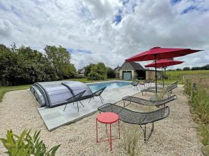 grupa leżaków i parasoli przy basenie w obiekcie Maison spacieuse avec spa et jardin dans le bocage normand - FR-1-497-254 w mieście Mantilly