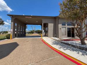 a building with a garage with a tree in front of it at Studio 6 Suites Mesquite, TX – Gross Rd. in Mesquite